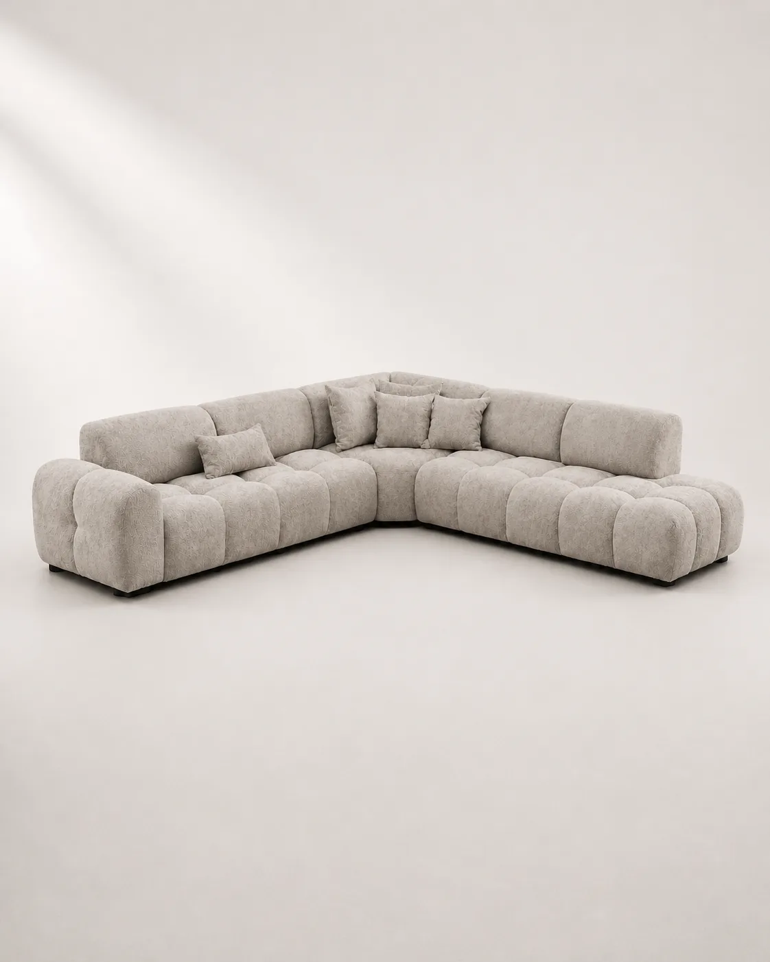 Light gray bubble-tufted L-shaped sofa with sculptural design.